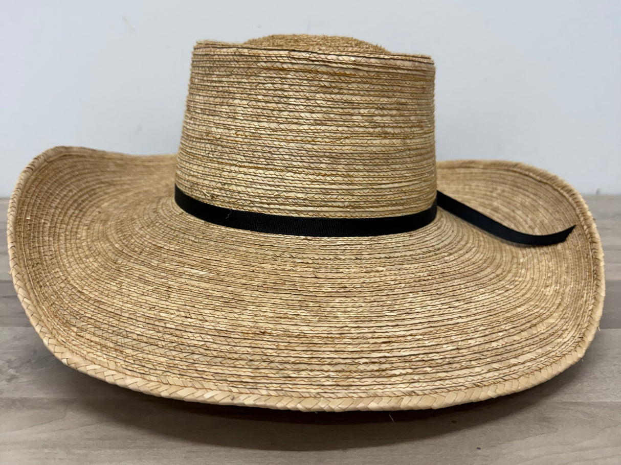 Wide-brimmed straw hat with a black band on a wooden surface