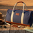 Pilbara Overnight Bag in navy blue with leather trims on rustic timber surface