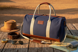 Pilbara Overnight Bag in navy blue with leather trims on rustic timber surface