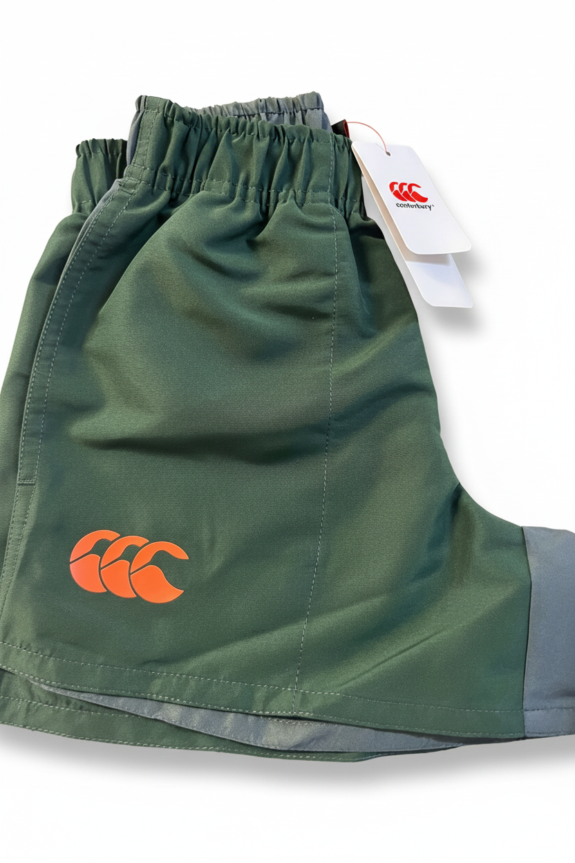 Olive green Canterbury kids Harletic shorts with orange logo on a plain white background